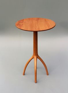 a wooden table with two legs and a round top on a grey background, in the shape of an x - leg