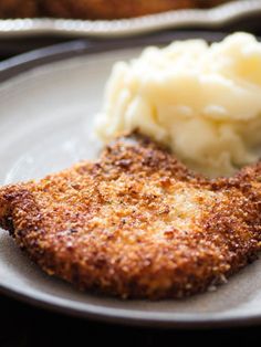 breaded fried pork chops on a plate with mashed potatoes