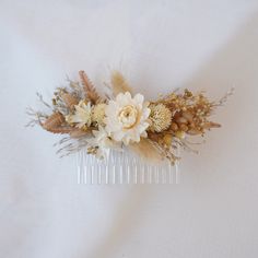 a hair comb with flowers and feathers on it sitting on a white cloth covered table