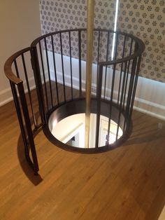 a spiral staircase in an empty room with wood flooring and wall paper on the walls