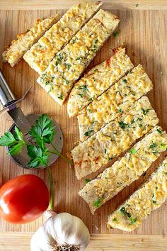 several slices of bread on a cutting board with tomatoes, garlic and parsley next to it