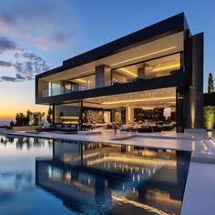 a large house with a swimming pool in front of it at sunset or sunrise time