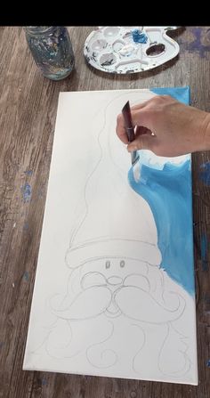 a person is drawing on a piece of paper with a brush and watercolors