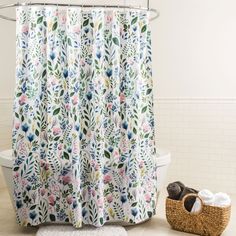 a bathroom with a flower shower curtain next to a basket