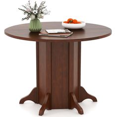 a wooden table with a bowl of fruit on it and flowers in a vase next to it