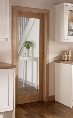 a kitchen with wooden floors and white cupboards next to a door that leads to a balcony