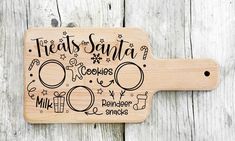 a wooden cutting board with the words treats santa written in black ink on it, along with other christmas related items