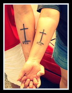 two people holding hands with cross tattoos on them