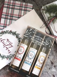 three bottles of olive oil sitting on top of a table next to napkins and christmas decorations