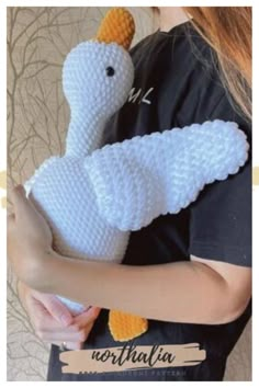 a woman is holding a knitted white bird