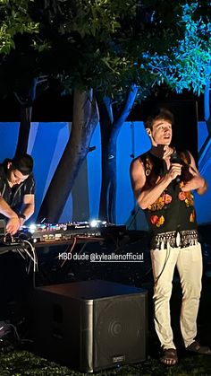 two men standing next to each other in front of a dj's equipment set