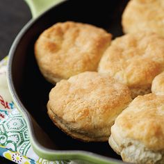 some biscuits are in a pan on a tablecloth with a green and white napkin