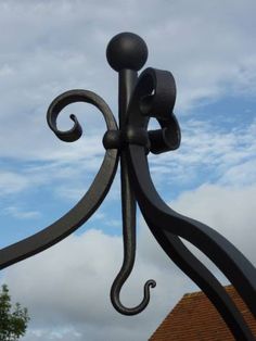 a black iron gate with an intricate design on it's side and blue sky in the background