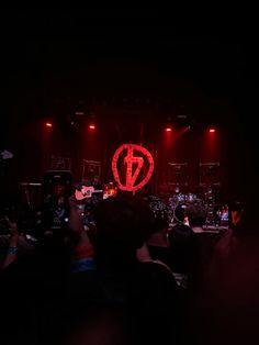 a group of people standing on top of a stage with red lights in the dark