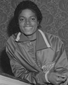 an old photo of a woman smiling for the camera with her jacket over her shoulders