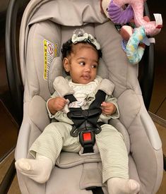 a baby sitting in a car seat next to two stuffed animals