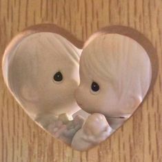 a heart shaped mirror with two baby elephants in the middle and one being held up to it's face