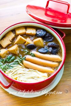 a bowl of soup with tofu, noodles and spinach in it on a wooden table