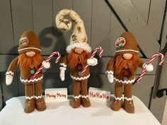 three christmas gnomes holding candy canes on top of a table