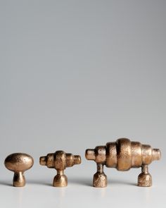 three antique brass knobs are lined up on a white surface, one is turned upside down