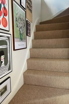 a staircase with pictures on the wall and carpeted steps leading up to the second floor