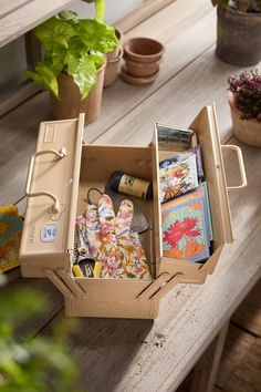 an open suitcase sitting on top of a wooden table next to potted plants and books