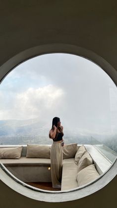 a woman standing on top of a building looking out at the sky through a round window