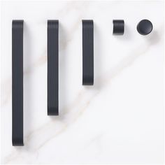 three black handles and two knobs on a white marble surface