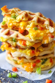 a stack of waffles topped with eggs and vegetables