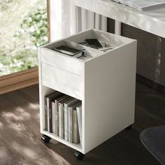 a white book shelf with books on it in front of a window and wooden floor