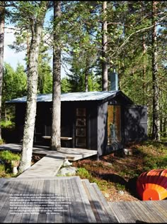 a small cabin in the woods with a deck and large orange object on the ground