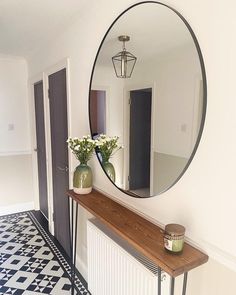 a mirror on the wall above a table with vases and flowers in front of it