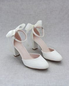 a pair of white shoes with bows on them