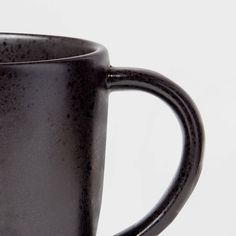 a black coffee mug sitting on top of a white table