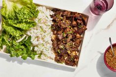 a white plate topped with meat and rice next to two bowls of vegetables on a table