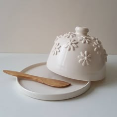 a white cake dish with a wooden spoon on it and a serving platter next to it