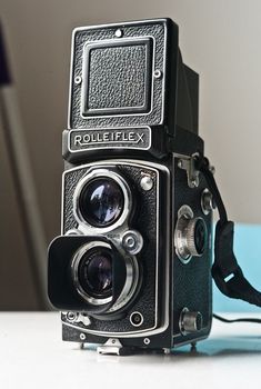 an old fashioned camera sitting on top of a white table next to a blue wall