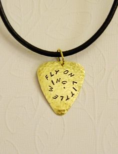 a gold guitar pick with the words fly on and whizz written on it