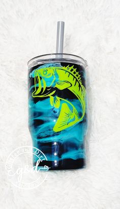 a blue and yellow fish tumbler cup on a white furnishing with a straw in it