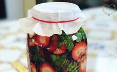 a jar filled with strawberries sitting on top of a table