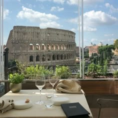 a table with a wine glass on it in front of the colossion, rome