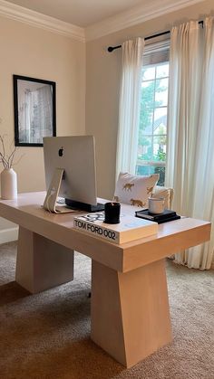 a laptop computer sitting on top of a wooden desk in front of a large window