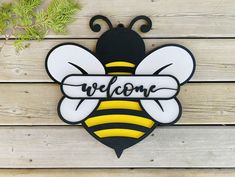 a wooden sign that says welcome with a bee on it's back and the word,