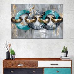 an abstract painting with gold, silver and blue rings on it's wall in a living room