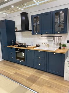 a large kitchen with blue cabinets and wooden flooring in an open concept space that is well lit