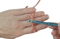 two hands are holding a pair of crochet hooks