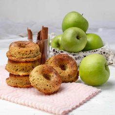 some apples and cinnamon sticks are on a pink towel next to some green apple's