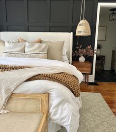 a bed with white linens and pillows in a bedroom next to a wooden floor