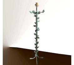 a tall metal candle holder with leaves on it's sides and a single candle in the middle