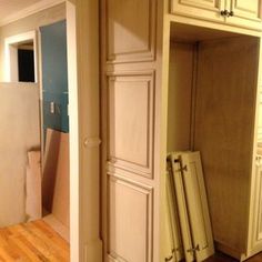 an empty room with wooden floors and white cabinets in the corner, next to a doorway that leads into another room